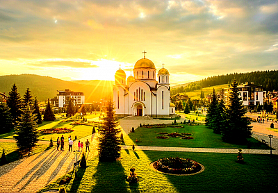 Источна капија Златибора - Источна капија Златибора представља домен импресивног крашког рељефа и вековне традиције која се огледа у хармоничном преплитању геоморфолошких феномена и аутентичног народног градитељства, обухватајући пределе Сирогојна, Рожанства и Гостиља. Овај део планинског масива карактерише доминација тријаских кречњака чија је велика порозност омогућила стварање сложених подземних система, међу којима се издваја Стопића пећима са својим монументалним бигреним кадама које представљају врхунски еволутивни доказ снаге флувијалне ерозије и калцификације. У непосредној близини, село Сирогојно чува јединствени комплекс „Старо село“, музеј на отвореном који није само збирка брвнара из деветнаестог века, већ архитектонски запис о начину живота, организацији породичних задруга и прилагођавању човека суровим климатским условима златиборског истока. Економска основа овог подручја вековима је почивала на преради вуне и дрвета, где су веште плетиље из Сирогојна својим аутентичним радом позиционирале овај крај на светску мапу модне индустрије, док су бачвари из Рожанства усавршили израду дрвених судова од храстовине и боровине који су неопходни за сазревање чувених златиборских млечних производа. Хидрографију источне капије обележава река Катушница и спектакуларни Гостиљски водопад, чији се млазеви са тридесет метара висине обрушавају преко кречњачких литица, стварајући микроамбијент богат влагом и негативним јонима који погодују развоју специфичних врста маховина и алги. Биодиверзитет овог појаса обухвата густе шуме букве и јеле које постепено прелазе у цветне пашњаке богате лековитим биљем као што су линцура, босиљак и мајчина душица, које мештани сакупљају користећи знања преношена са колена на колено. Духовни и друштвени центар источног Златибора одувек су биле сеоске порте и заједнички пашњаци, места где се уз звук гусала и песму из вика славила слобода и чувао идентитет који је кроз историју био изложен сталним искушењима. Сваки камени зид, сваки дрвени амбар и сваки усечени пут у источној капији Златибора сведоче о неуништивој вези између природе која пружа ресурсе и човека који те ресурсе користи са дубоким поштовањем, градећи наслеђе које превазилази границе локалне историје и постаје део универзалне културне баштине. Инспирација коју овај предео нуди уметницима, истраживачима и путницима лежи у његовој сировој лепоти и тишини коју прекида само хук водопада или звук бачварског чекића, подсећајући на време када је рад био молитва, а природа највеће светилиште.