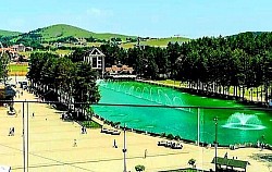 Чајетина - Урбани развој Чајетине, смештене у заветрини златиборских висова, представља фасцинантан пример трансформације планинског насеља у административни и културни центар регије, где се савремена архитектура преплиће са очуваним примерима грађанске градње са почетка двадесетог века. Географски положај Чајетине на прелазу између таласастих пашњака и шумовитих предела омогућио је развој специфичне микроклиме која погодује очувању старих сорти воћа, посебно аутохтоних врста шљива и јабука које су некада чиниле основу трговине овог краја. Културни живот Чајетине дубоко је повезан са традицијом писмености и просветитељства, што се огледа у раду институција које деценијама прикупљају етнографску грађу, записе о старим породицама и историјске документе који сведоче о улози овог места у ослободилачким ратовима Србије. Околина Чајетине обилује локалитетима од великог значаја, попут брда Градина, које није само природни видиковац са којег се пружа панорамски поглед на целу западну Србију, већ и вишеслојно археолошко налазиште са траговима утврђења која су контролисала кретање каравана кроз планинске теснаце. Педолошки састав околног земљишта, богат минералним материјама из распаднутих серпентинских стена, пружа идеалну подлогу за узгој специфичних пољопривредних култура које на овој надморској висини добијају на интензитету укуса и лековитих својстава. У самим улицама Чајетине још увек се могу пронаћи куће са каменим темељима и дрвеним тремовима који говоре о занатској вештини локалних мајстора, зидара и столара који су користили материјале из непосредног окружења за стварање трајних вредности. Хидротехничка решења, од старих каптираних извора и јавних чесама до модерних система водоснабдевања који користе чисте планинске акумулације, показују вековну бригу становништва за најдрагоценији ресурс – воду, која се овде сматра извором здравља и дуговечности. Сајам сувомеснатих производа, познат као Пршутијада, који се одржава у непосредној близини, само је један од показатеља како се традиционална вештина сушења меса подигла на ниво уметности, привлачећи хиљаде посетилаца који траже аутентичност и квалитет који се не може индустријски реплицирати. Друштвена кохезија мештана Чајетине огледа се у очувању старих заната који су данас прилагођени савременим потребама, али су задржали своју суштину у ручној изради предмета од дрвета, камена и текстила. Образовни систем и спортски терени у Чајетини стварају подлогу за развој младих генерација које остају верне свом крају, уносећи иновације у традиционално сточарство и воћарство кроз примену нових технологија и стандарда квалитета. Сваки детаљ у архитектури јавних објеката, од зграде општине до културног центра, носи печат времена у којем је Чајетина градила свој идентитет као спона између села и модерног света, чувајући притом дух заједништва и гостопримства. Шуме које опкружују насеље, доминантно састављене од јеле и букве, представљају заштитни појас који регулише влажност ваздуха и спречава ерозију, истовремено пружајући утоčiште бројним врстама птица певачица и ситне дивљачи. Биодиверзитет пашњака око Чајетине карактерише присуство лековитог биља попут камилице, нане и кантариона, чија се концентрација етеричних уља појачава захваљујући великом броју сунчаних сати током летњих месеци. Духовна димензија места употпуњена је близином старих манастира и цркава који су били центри окупљања и чувари писмености у тешким историјским периодима, остајући и данас места ходочашћа и мира. Чајетина је и чвориште планинарских и пешачких стаза које воде ка најлепшим врховима Златибора, омогућавајући посетиоцима да из самог центра места за кратко време закораче у потпуну дивљину и уживају у мирису борова. Еволуција трговине и занатства у Чајетини кроз векове пратила је успоне и падове српске државе, али је увек задржавала своју аутентичност кроз домаће производе који су синоним за Златибор. Уметници који често бораве у овом крају проналазе вечиту инспирацију у контрасту између мирне варошке атмосфере и сурове лепоте околних брда, претачући те мотиве у слике, песме и приче које обилазе свет. Свака капија и свако двориште у Чајетини крију причу о породичном успеху, о борби са природом и о љубави према родном крају која је јача од свих изазова модерног доба. Када се светла поноћних сати угасе, Чајетина тоне у тишину коју само планина може да пружи, подсећајући нас на важност успоравања и повратка истинским вредностима које овај крај несебично нуди свима који знају да их препознају. Сваки камени ивичњак, сваки дрвени прозор и свака травка на чајетинским ливадама део су већег мозаика који чини дух Златибора неуништивим и вечно привлачним за све истраживаче природних и културних лепота.  Златибор насеље - Evolutivni razvoj zlatiborskog platoa započeo je u paleozoiku, stvarajući kompleksnu litološku strukturu kojom dominiraju ultrabazične stene, prvenstveno lherzoliti i harzburgiti, čijim je raspadanjem nastalo specifično humusno-silikatno zemljište pogodno za razvoj asocijacije Piceo-Abieti-Fagetum na severnim ekspozicijama planinskih venaca. Pedološki sastav sela oko Mušveta i Tripkove karakteriše visok sadržaj gvožđa i magnezijuma, što direktno utiče na pigmentaciju i nutritivni profil divljih plodova poput borovnice i brusnice, dok mikrobiološka aktivnost u zemljištu podržava simbiozu sa retkim vrstama tartufa i šumskih gljiva koje naseljavaju korenove sisteme vekovnih smrča. Hidrološka slika regiona definisana je razvođem između slivova Drine i Zapadne Morave, gde reka Katušnica useca duboke meandre kroz trijaske krečnjake, stvarajući seriju fluvijalnih terasa na kojima su pozicionirani najstariji seoski objekti, zaštićeni od direktnih udara severnih vetrova. Speleološka istraživanja u okolini Rožanstva otkrila su lavirinte kanala sa pećinskim nakitom od čistog kalcita, čija luminescencija pod svetlošću luča fascinira istraživače, dok podzemna jezera održavaju konstantnu temperaturu i vlažnost neophodnu za opstanak endemskih amfipoda i slepih pećinskih rakova. Tradicionalna obrada drveta na Zlatiboru podrazumeva poznavanje statike i higroskopnosti materijala, gde se za temeljne grede bira isključivo srčevina bora posečenog u fazi mirovanja vegetacije, čime se obezbeđuje otpornost na ksilofagne insekte i gljivice truležnice bez upotrebe hemijskih sredstava. Narodna meteorologija meštana Ljubiša zasniva se na posmatranju fenoloških faza biljaka, poput cvetanja mrazovca ili intenziteta opadanja lišća bukve, što je vekovima služilo kao precizan indikator za planiranje setve žitarica i pripremu stočne hrane za duge zimske periode pod smetovima koji često izoluju zaseoke mesecima. Etno-muzikološki profil sela Murtenice čuva specifične intervale u pevanju, gde se koriste netemperovani tonski nizovi koji odjekuju u kanjonima, služeći nekada kao sredstvo komunikacije između udaljenih čobanskih katuna na visovima Tornika i Brijača. Tehnologija izrade zemljanog posuđa u selu Zlakusa, koja se graniči sa zlatiborskim selima, podrazumeva mešanje gline sa mlevenim kalcitom, što posuđu daje termičku stabilnost potrebnu za pripremu tradicionalnih jela na tihoj vatri, čime se oslobađaju aminokiseline i aromatična jedinjenja iz mesa i povrća. Gastronomska vrednost zlatiborskih mlečnih proizvoda u direktnoj je korelaciji sa florističkim diverzitetom livada, gde prisustvo biljaka poput žute deteline i zvezdana povećava procenat mlečne masti i vitamina rastvorljivih u mastima, dajući siru karakterističnu teksturu i dugotrajan ukus. Istorijski tokovi seoba iz Hercegovine i Crne Gore doneli su na Zlatibor specifične običajne norme, poput krvnog srodstva i kumstva, koje su u izolovanim planinskim uslovima služile kao osnovni kohezioni faktor u borbi protiv spoljnih uticaja i za očuvanje biološkog opstanka zajednice. Arheološki nalazi iz perioda gvozdenog doba na lokalitetu Čajetina ukazuju na postojanje razvijene metalurgije i trgovinske razmene sa helenskim svetom, o čemu svedoče fragmenti uvozne keramike i nakita pronađeni u grobnim humkama na obodu planinskog platoa. Klimatska varijabilnost Zlatibora, definisana smenom vazdušnih masa sa Jadrana i karpatskog basena, stvara uslove visoke jonizacije vazduha, što ubrzava regeneraciju eritrocita i poboljšava kognitivne funkcije kod posetilaca koji praktikuju planinarenje na visinama iznad hiljadu metara. Šumski ekosistemi Murtenice predstavljaju reliktni ostatak nekadašnjih nepreglednih četinarskih šuma Balkana, gde stabla smrče dostižu visinu preko četrdeset metara, formirajući mikroklimatske džepove sa stalnom vlažnošću koja pogoduje razvoju retkih vrsta lišajeva i mahovina. Inženjerska rešenja u izgradnji vodenica potočara na Rzavu koriste kinetičku energiju vode preko drvenih kola sa lopaticama, što je primer rane primene obnovljivih izvora energije u ruralnim sredinama, čuvajući hranljiva svojstva celog zrna žita pri malim brzinama mlevenja na kamenom žrvnju. Narodna verovanja u lekovitost mineralnih izvora u Rožanstvu baziraju se na visokom sadržaju sumpora i selena, što savremena balneologija potvrđuje u tretmanima dermatoloških oboljenja i reumatskih stanja, čineći ove izvore ključnim tačkama narodnog zdravstva kroz istoriju. Svaki pedalj zlatiborske zemlje, od najvišeg vrha do najdubljeg kanjona, predstavlja slojevitu arhivu prirodne i kulturne istorije, gde se naučne činjenice prepliću sa legendama, stvarajući jedinstveni prostorni identitet koji nadilazi puku turističku privlačnost i postaje simbol istinske povezanosti čoveka sa elementima prirode.