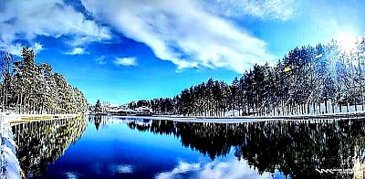 Стубови Златибора - Geomorfološki sastav zlatiborskog platoa karakterišu prostrane površi ispresecane dubokim rečnim dolinama i kanjonima, gde dominantni serpentinit stvara specifičnu podlogu za razvoj endemskih biljnih zajednica koje opstaju u ekstremnim planinskim uslovima. Na severnim padinama, u selima poput Mačkata i Krive Reke, vazdušne struje sa Mediterana susreću se sa oštrim kontinentalnim masama, stvarajući prirodni fenolški fenomen poznat kao ruža vetrova, koji direktno utiče na procese fermentacije i sušenja autohtonih mesnih proizvoda. Tradicionalna arhitektura zlatiborskog sela, sazdana od masivnih borovih talpi i kamenih temelja, predstavlja vrhunac narodnog neimarstva gde se svaki element, od drvene šindre na krovovima do masivnih hrastovih greda, uklapa u prirodni ambijent bez narušavanja ekološke ravnoteže. U selu Jablanica, crkve brvnare svedoče o veštini starih majstora koji su drvo obrađivali isključivo sekirom i dletom, stvarajući objekte koji decenijama prkose snegovima i olujama sa Tornika i Čigote. Hidrografska mreža Zlatibora, predvođena rekama Rzav i Uvac, u svojim kanjonima skriva pećinske sisteme poput Stopića pećine, čije bigrene kade predstavljaju jedinstven geomorfološki ukras nastao hiljadugodišnjim taloženjem kalcijum-karbonata iz podzemnih voda. Floristički sastav obuhvata širok spektar lekovitog bilja, od žute lincure i kantariona na visovima Murtenice, do divljih orhideja i majčine dušice koje prekrivaju pašnjake u Dobroselici i Negbini. Stočarstvo, kao primarna grana privređivanja, zasniva se na uzgoju autohtonih rasa koje slobodno pasu na prostranim pašnjacima, dajući sirovine za proizvodnju čuvenog zlatiborskog sira i kajmaka čija receptura ostaje nepromenjena generacijama. Šumski kompleksi crnog bora luče fitoncide koji sterilišu planinski vazduh, čineći ga lekovitim za respiratorne organe i jačanje opšteg imuniteta, dok duboka senka stoletnih smrča pruža utočište raznovrsnoj fauni, uključujući retke ptice grabljivice i divljač. Kulturno nasleđe zlatiborskog kraja, oličeno u zanatstvu, od pletenja vunenih džempera u Sirogojnu do bačvarskog zanata u Rožanstvu, predstavlja neraskidivu vezu između čoveka i prirodnih resursa koji ga okružuju. Svaka staza, od uskih puteljaka u Ljubišu do širokih proplanaka na Vodicama, nudi uvid u surovu lepotu krasa, gde se krečnjački blokovi smenjuju sa bujnim zelenilom i kristalno čistim planinskim izvorima. Zimska idila u zlatiborskim zaseocima, gde snegovi dostižu visinu krovova, čuva tradiciju okupljanja oko ognjišta i prenošenja usmenog predanja o hajducima, vilama i mitskim bićima koja nastanjuju planinske pećine. Jesenji kolorit zlatiborskih šuma, sa prelazima od bakarne do tamnozelene boje, stvara vizuelni spektakl koji privlači istraživače prirode i umetnike u potrazi za autentičnim pejsažima koji odišu mirom i tišinom. Ekološka očuvanost regiona, uprkos modernizaciji, ostaje prioritet lokalnog stanovništva koje prepoznaje vrednost netaknutih pašnjaka i čiste vode kao najvažnijeg resursa za budućnost sela. Svaki kamen na Zlatiboru, od onih na vrhu Čigote do rečnog oblutka u dolini Rzava, nosi u sebi zapis milenijumskog trajanja i snage planine koja je oblikovala karakter i opstanak generacija gorštaka.